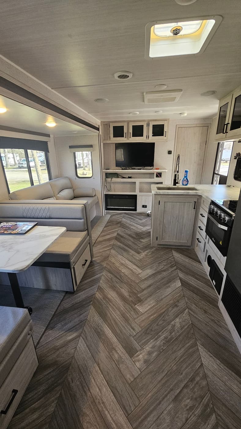 Interior of a Wanderous camper showing the sofa, dinette, kitchen, and herringbone floor